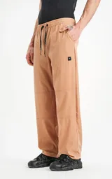 Pantalón beige de corte ancho, con cintura y puños elásticos, bolsillos laterales y logo estampado en la pierna.