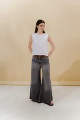 Pantalón de jean gris con efecto lavado, tiro medio, corte acampanado y ruedo con cortes curvos.