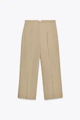 Pantalón culotte color beige de tiro alto con bolsillos de vivo en delantero, pierna ancha y cierre frontal con cremallera y gancho metálico.