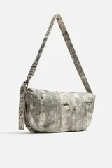 Bolso de hombro color gris con efecto desgastado, fabricado en tejido de algodón. Tiene un compartimento principal con cierre de cremallera, un bolsillo interior con cremallera y asa de hombro ajustable.