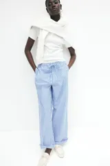 Pantalón de corte holgado en algodón a rayas verticales azules y blancas. Modelo de tiro alto con cintura elástica fruncida y cordón para ajustar. Piernas anchas con bolsillos laterales discretos.