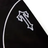 Conjunto deportivo negro con vivos blancos, compuesto por campera con cierre y pantalón con cordón ajustable. La campera tiene cuello alto, cierre frontal y logo de la marca bordado en el pecho. El pantalón tiene bolsillos laterales y logo bordado en la pierna.