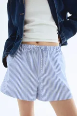 Short de algodón con cintura elástica y cordón ajustable. Diseño a rayas verticales azules y blancas.