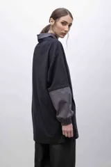 Remerón negro con cuello camisero gris, mangas largas grises con puños elásticos y bolsillo con solapa en el pecho.