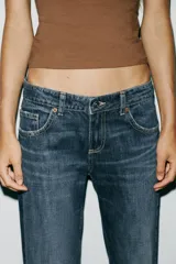 Pantalón de jean celeste claro, de tiro bajo, corte wide leg y largo hasta el tobillo. Tiene cinco bolsillos, cierre frontal con cremallera y botón metálico.