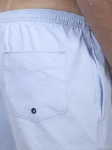 Short de baño verde con estampado de margaritas blancas y cordón ajustable naranja.