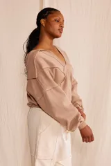 Sweater de cuello polo amplio con bolsillo frontal, diseño de costuras desflecadas.