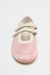 Zapato tipo bailarina deportiva color rosa con efecto satinado, puntera redondeada y doble tira con ajuste adhesivo.