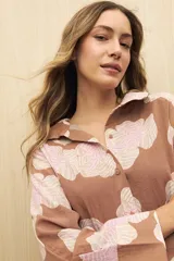 Vestido camisero midi color marrón con estampado de flores rosas, cinturón marrón y mangas largas.