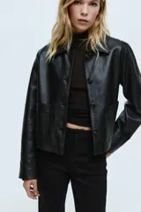 Jean de denim negro con leve stretch, corte ajustado de cintura a cadera y acampanado desde la rodilla al bajo. Es de tiro alto con cierre, botón oculto y corchete. Tiene bolsillos traseros decorativos y pliegues delanteros y traseros.