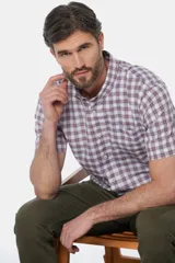Camisa de manga corta con estampado a cuadros en tonos blanco, rojo y azul. Tiene cuello abotonado y corte clásico.