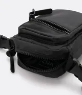 Bolso mini bandolera color blanco con correa ajustable, cierre de cremallera y bolsillo frontal con cremallera.