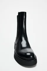 Botín Chelsea de cuero negro con elásticos laterales, tirador trasero y suela track con plataforma.