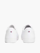 Zapatillas de corte bajo confeccionadas en una mezcla de piel y materiales sintéticos, color blanco. Presentan un diseño atemporal con cordones al tono, suela de goma vulcanizada y detalles distintivos de la marca Tommy Hilfiger, incluyendo el logo en el lateral, la lengüeta y el talón.
