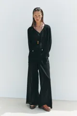 Pantalón negro de tiro alto con cintura elástica ajustable con cordones laterales, forro interior corto y pernera ancha.