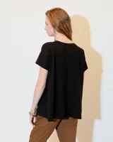 Remera de jersey flama 100% algodón, color negro, de línea A y fit relajado, con escote redondo, manga corta y recortes a los costados.