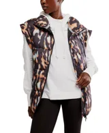Chaleco acolchado con estampado de camuflaje en tonos marrones y negros, con capucha y cierre frontal.