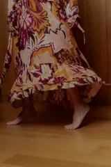 Maxi vestido con estampado floral en tonos naranja, rosa y borgoña. Tiene escote off-shoulder elastizado y mangas cortas con volados.