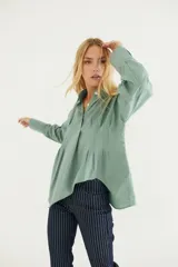Camisa color crema de algodón, con cuello polo, mangas largas con puños abotonados y corte asimétrico.