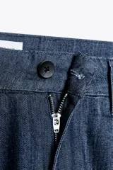 Pantalón de denim azul con pinzas delanteras, tiro medio, cintura con trabillas, bolsillos laterales y traseros.