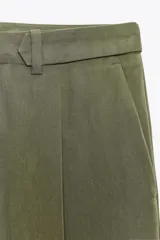 Pantalón verde militar de tiro medio con bolsillos delanteros y falsos bolsillos traseros. Detalle de pinzas en el delantero. Cierre frontal con cremallera y botón. Corte ancho.