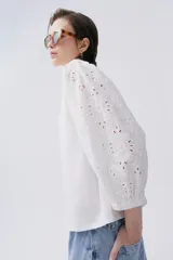 Blusa blanca con mangas abullonadas de bordado floral, y ajuste en las muñecas.