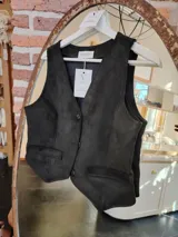 Chaleco negro de gamuza con corte sastre, cuello en V, cierre frontal con botones y bolsillos delanteros ribeteados.