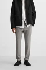 Pantalón slim fit negro confeccionado en tejido con elasticidad en ambas direcciones. Cuenta con bolsillos frontales y traseros de vivo con botón. Cierre frontal con cremallera y botón.
