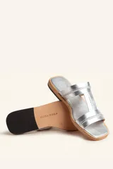 Sandalias bajas de cuero color marrón con costuras blancas a la vista.