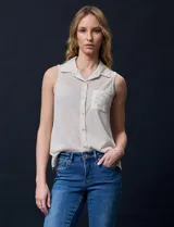 Blusa color crema sin mangas, con cuello camisero, cierre frontal con botones y bolsillo de crochet.