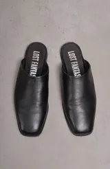 Sueco chato de cuero negro, con punta levemente cuadrada y plantilla con inscripción 'Lost Fantas'.