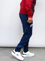 Pantalón de entrenamiento azul marino con logo de Umbro en blanco, corte ajustado y detalles en azul brillante en los tobillos.