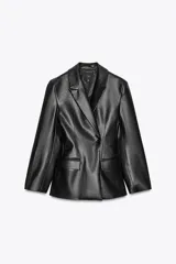 Blazer entallada negra de efecto piel, con cuello solapa y manga larga. Tiene bolsillos de plastrón en el delantero, costuras marcadas y forro interior combinado a tono. El cierre es frontal con botón interior y exterior.
