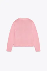 Chaqueta de punto rosa con cuello redondo y manga larga. Tiene bolsillos delanteros y cierre frontal con botones celestes.