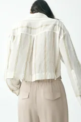 Camisa blanca a rayas verticales color beige, de corte recto, con cuello solapa, manga larga y dos bolsillos de parche en el pecho.