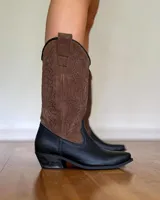 Botas de estilo cowboy con parte superior de gamuza marrón y puntera de cuero negro, diseño detallado en la caña.