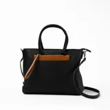 Cartera negra con doble asa corta y correa larga extraíble. Tiene bolsillo externo con cierre color marrón.