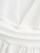 Top blanco con escote halter, espalda descubierta y volado en el ruedo.