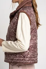 Chaleco marrón acolchado con cuello alto, cierre frontal con broches a presión y dos bolsillos delanteros con cordón ajustable.