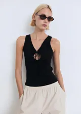 Top negro de punto fino, sin mangas, con cuello en V y detalle de lazo en el escote.