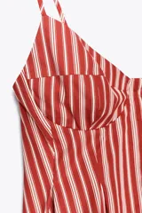 Top con estampado a rayas verticales rojas y blancas, escote pico, tirantes finos ajustables, detalle de pliegues y cierre frontal con botones.