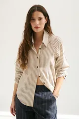 Camisa a rayas verticales color beige y blanco, con cuello clásico, botones marrones y mangas largas.
