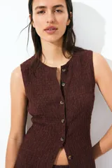 Chaleco marrón de punto texturizado con cuello redondo y botones frontales.