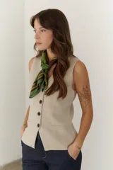 Chaleco gris de tejido de punto con cuello en V, cierre frontal con botones y bolsillos delanteros.