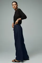 Pantalón de jean azul oscuro, de tiro alto y pierna ancha, con cintura elástica ajustable con cordones y bolsillos delanteros.