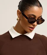 Sweater marrón de algodón con cuello camisero blanco, corte recto y mangas largas raglán.