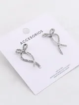 Par de aros colgantes plateados con forma de moño y pequeños brillantes incrustados.