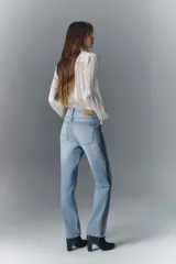 Pantalón de jean de tiro alto, denim azul rígido con lavado claro localizado, bigotes y apliques laterales de strass. Pierna recta.