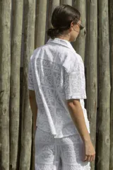 Camisa blanca con diseño calado, de corte recto, cuello camisero y mangas cortas.