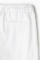 Pantalón blanco de lino liviano, corte recto, con elástico revestido y cordón ajustable en la cintura, bolsillos laterales y bolsillo trasero insertado.